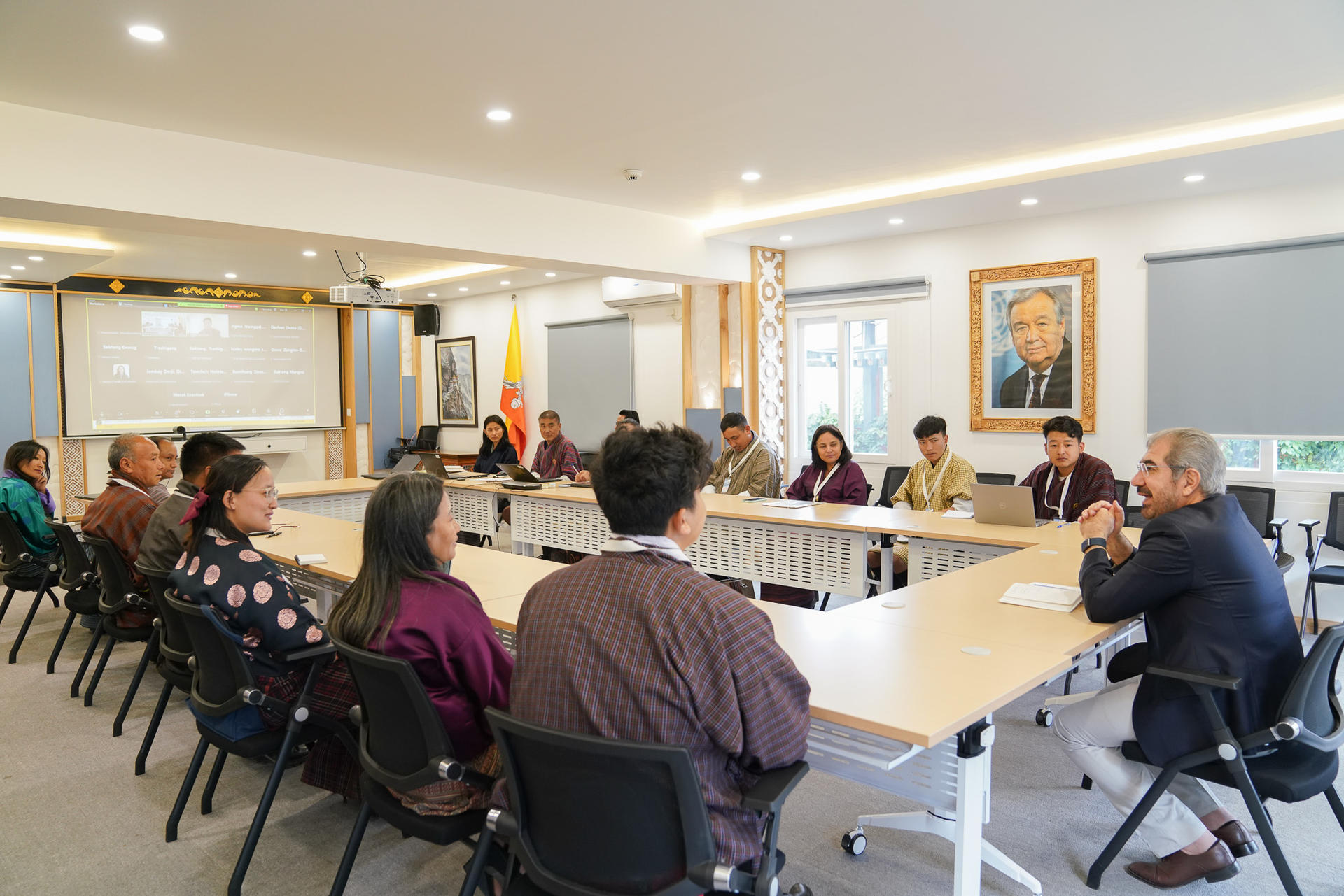 A group of people seated around a conference table in a modern meeting room.