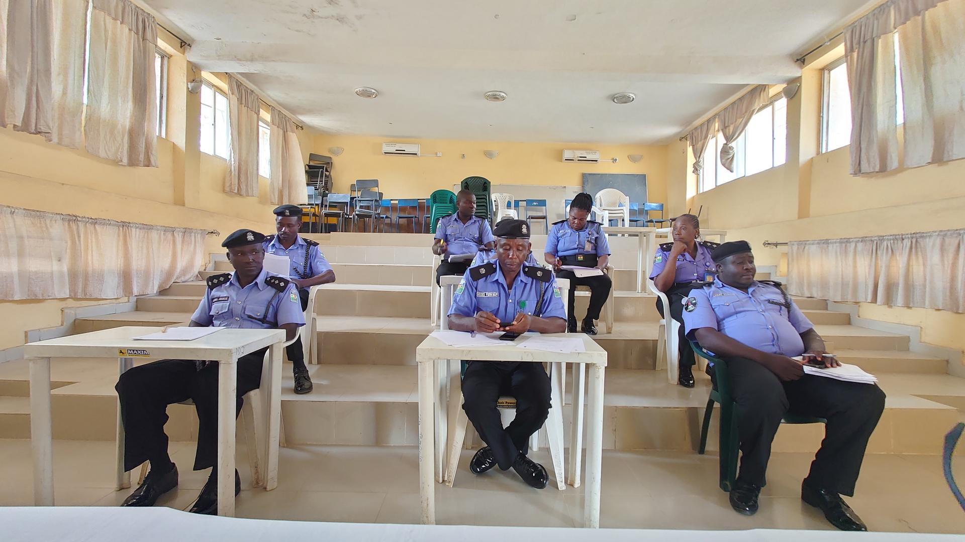 Group of uniformed officers seated at tables in a bright training room.