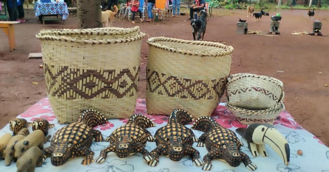 Canastos hechos a mano y figuras de animales de madera sobre una mesa en un entorno natural.
