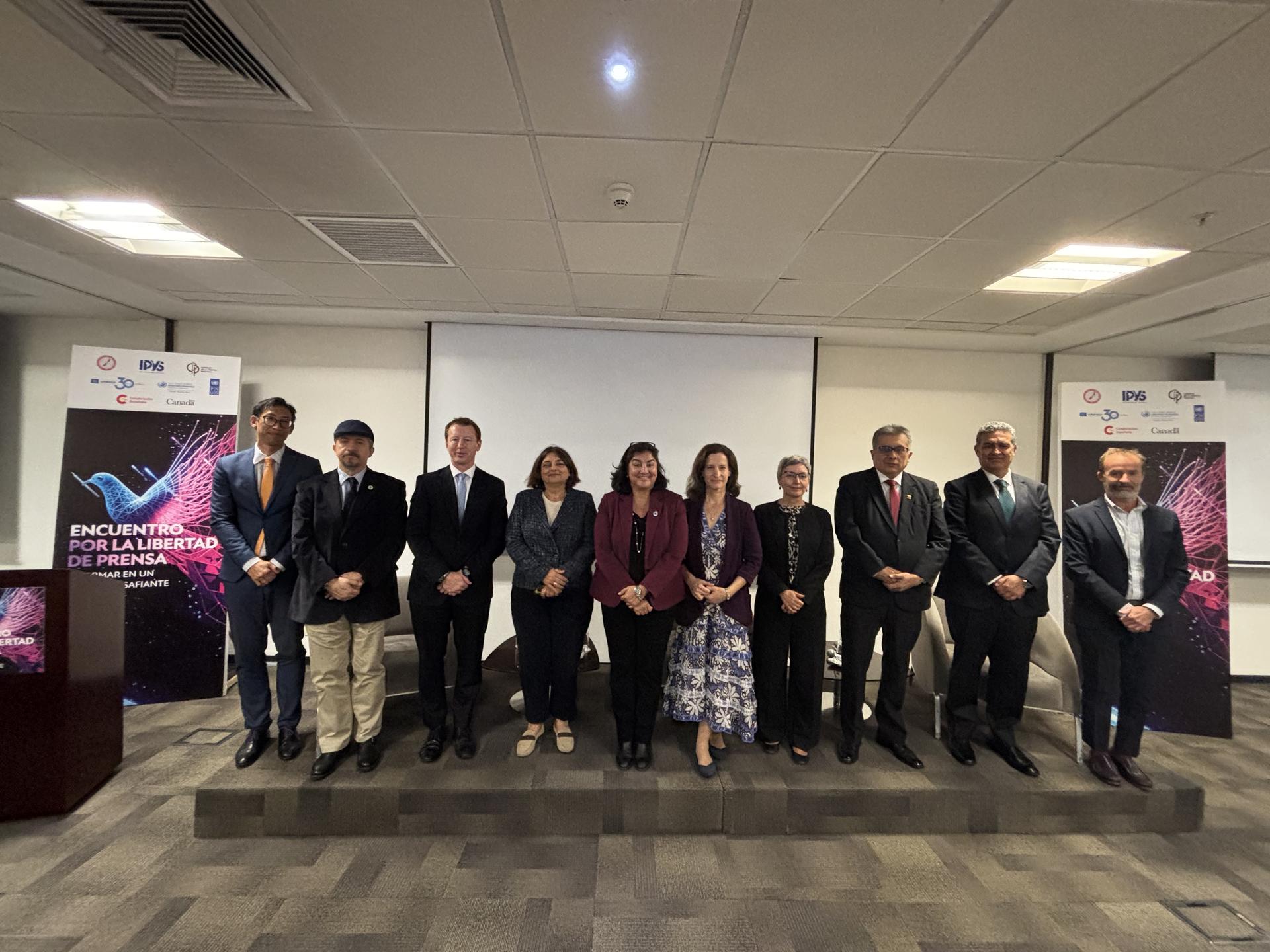 Group of professionals standing together at a conference event with banners in the background.