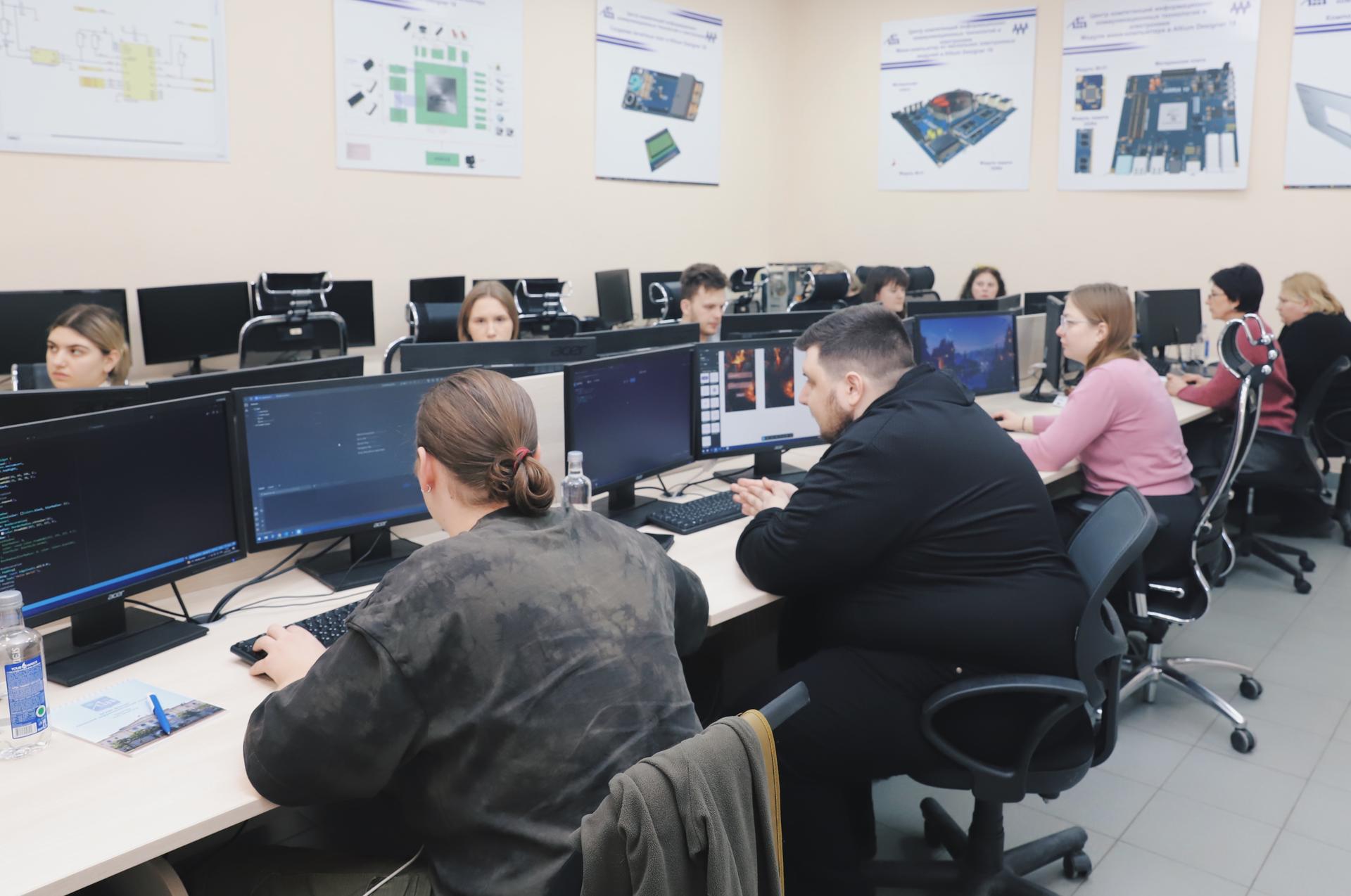 Students working at computers in a classroom environment, focused on their screens.