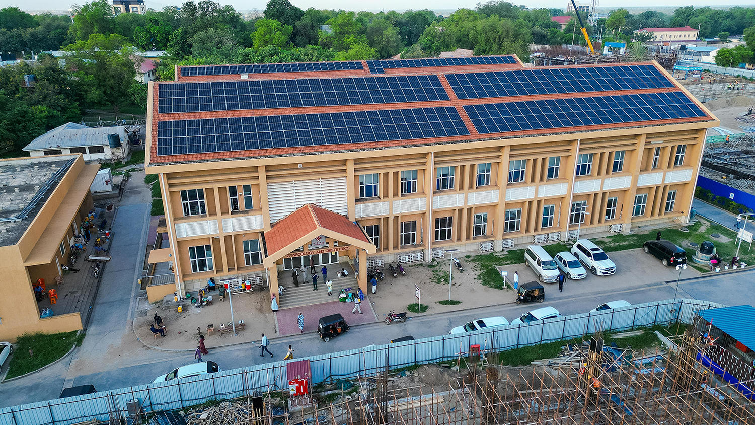 Aerial view of a hospital with solar panels and parked cars outside.