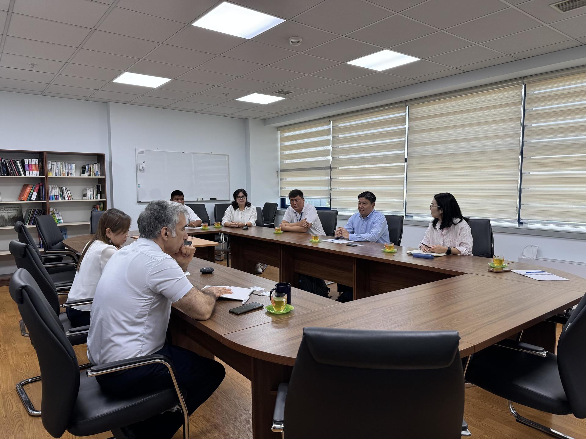 A group of people sitting around a large table in a bright meeting room.
