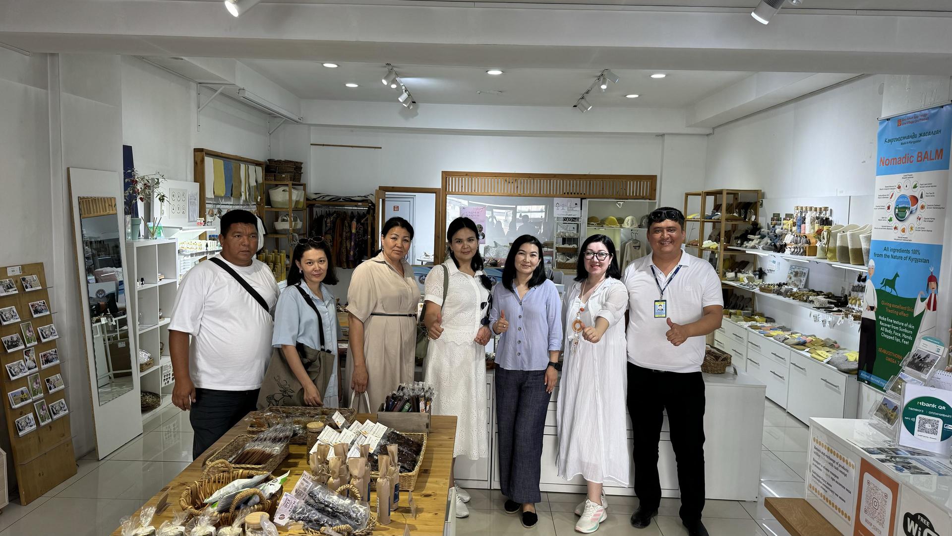 A group of six people stands in a brightly lit store filled with various products.