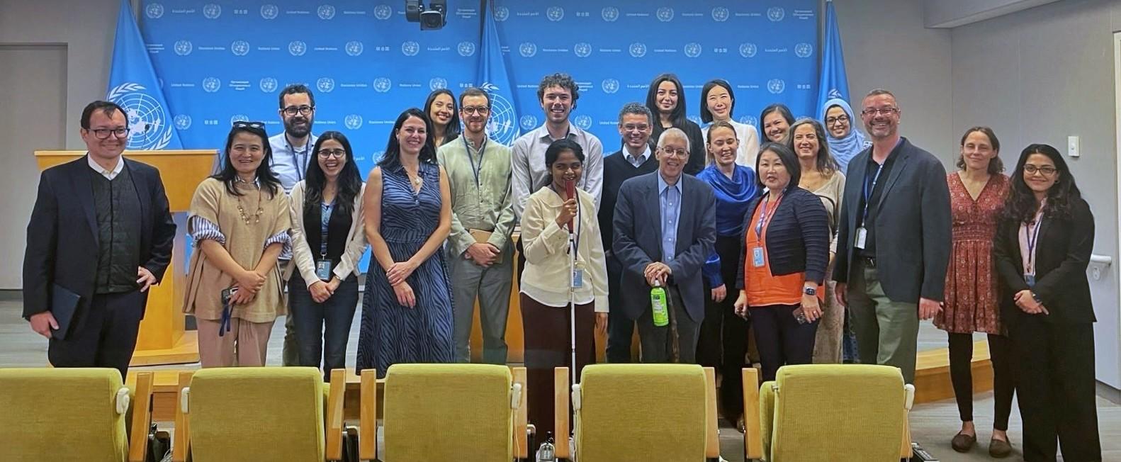 Group of diverse individuals posing together in a conference room at the UN.
