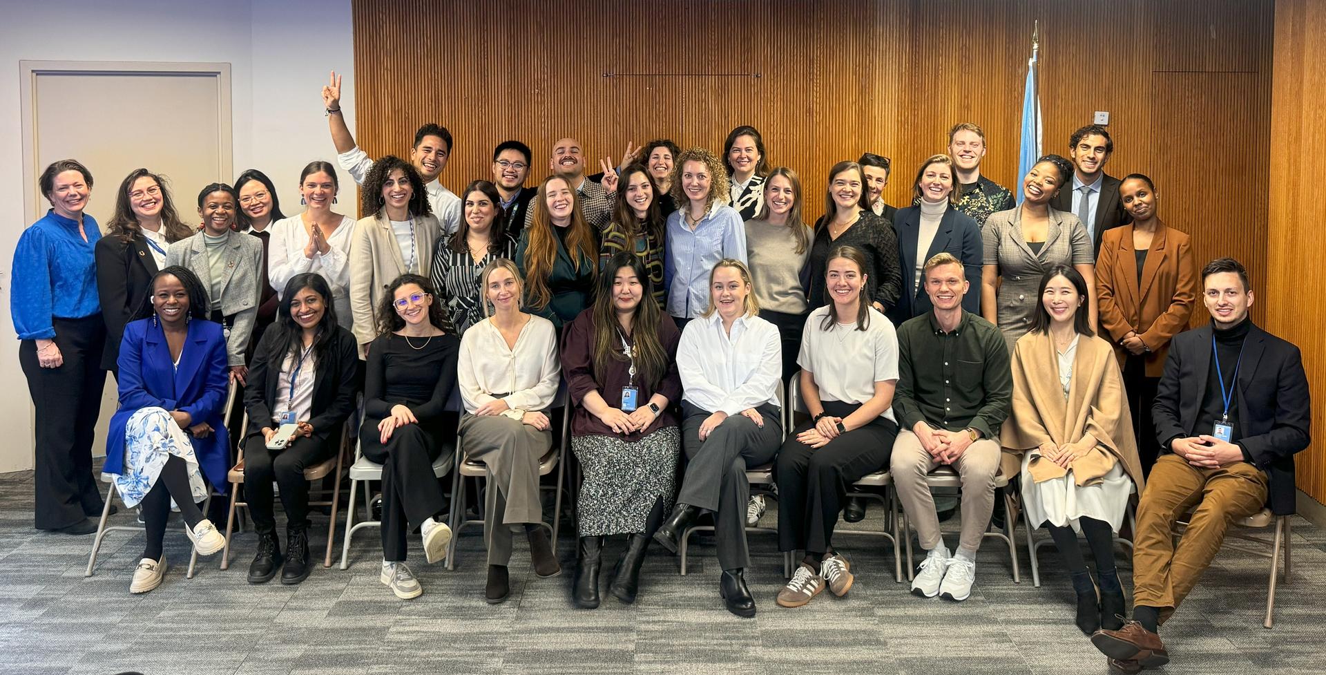 Group photo of diverse individuals posing together in a conference room setting.