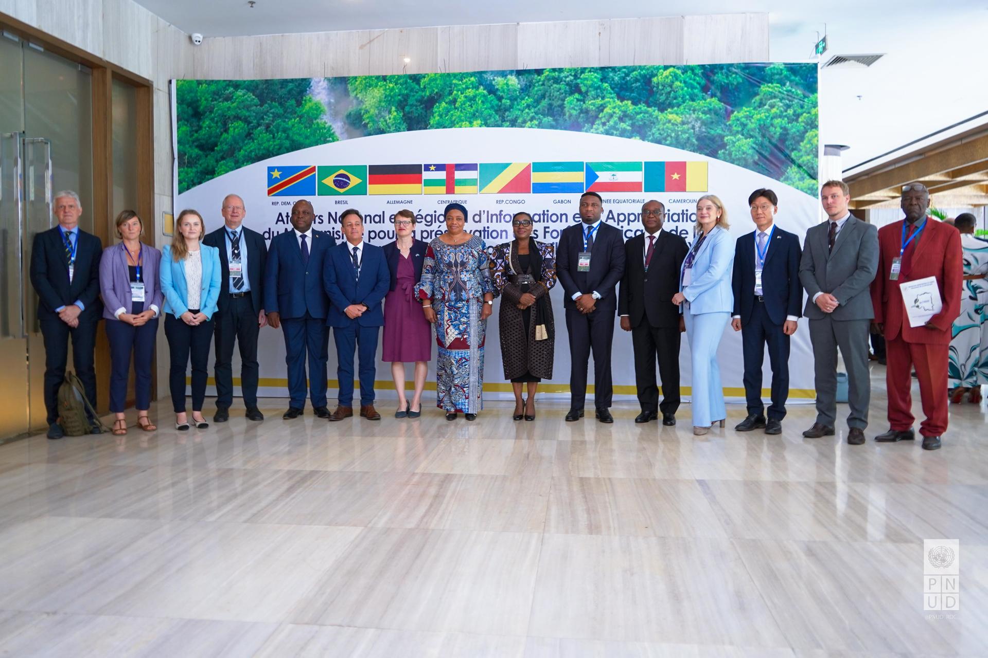 Group photo of delegates in formal attire, posing in a modern conference setting.