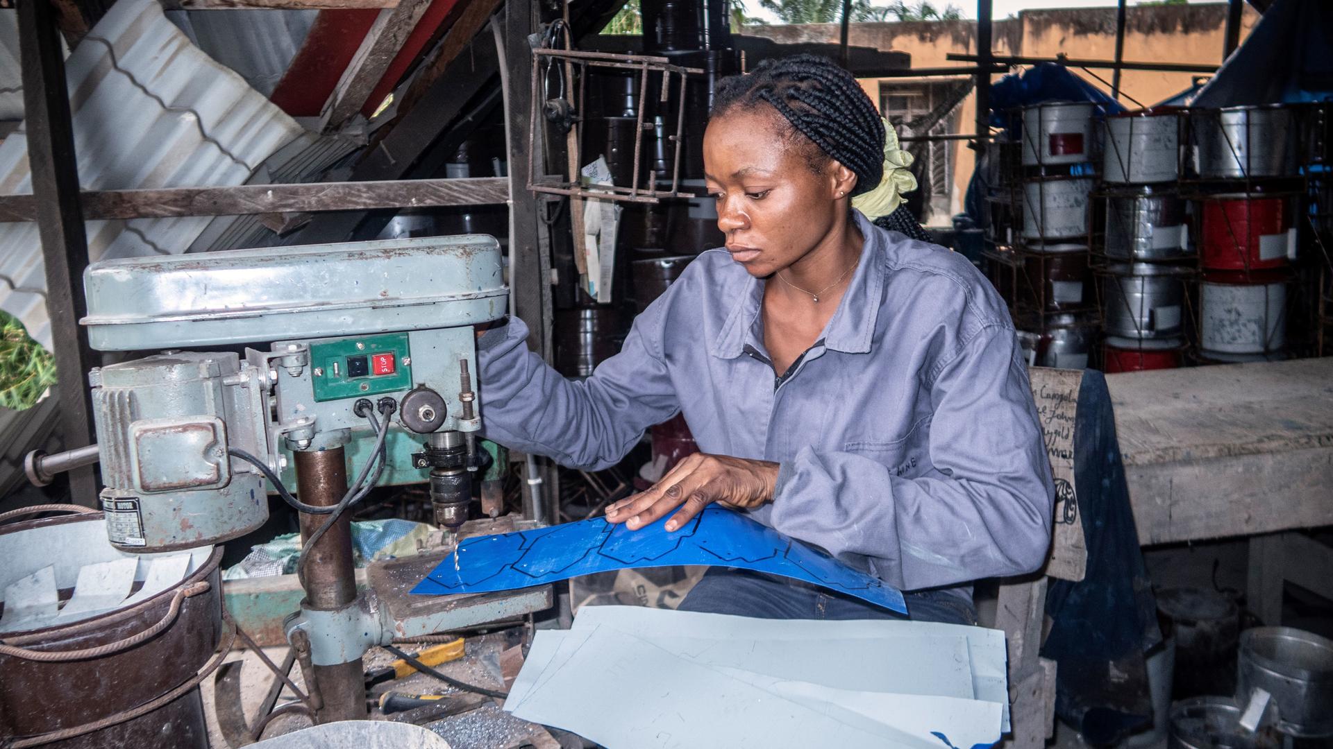 A woman working attentively at a sewing machine in a cluttered workshop.