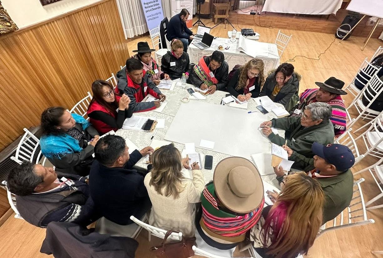 Aerial view of a diverse group of people seated around a large table, engaged in discussion.