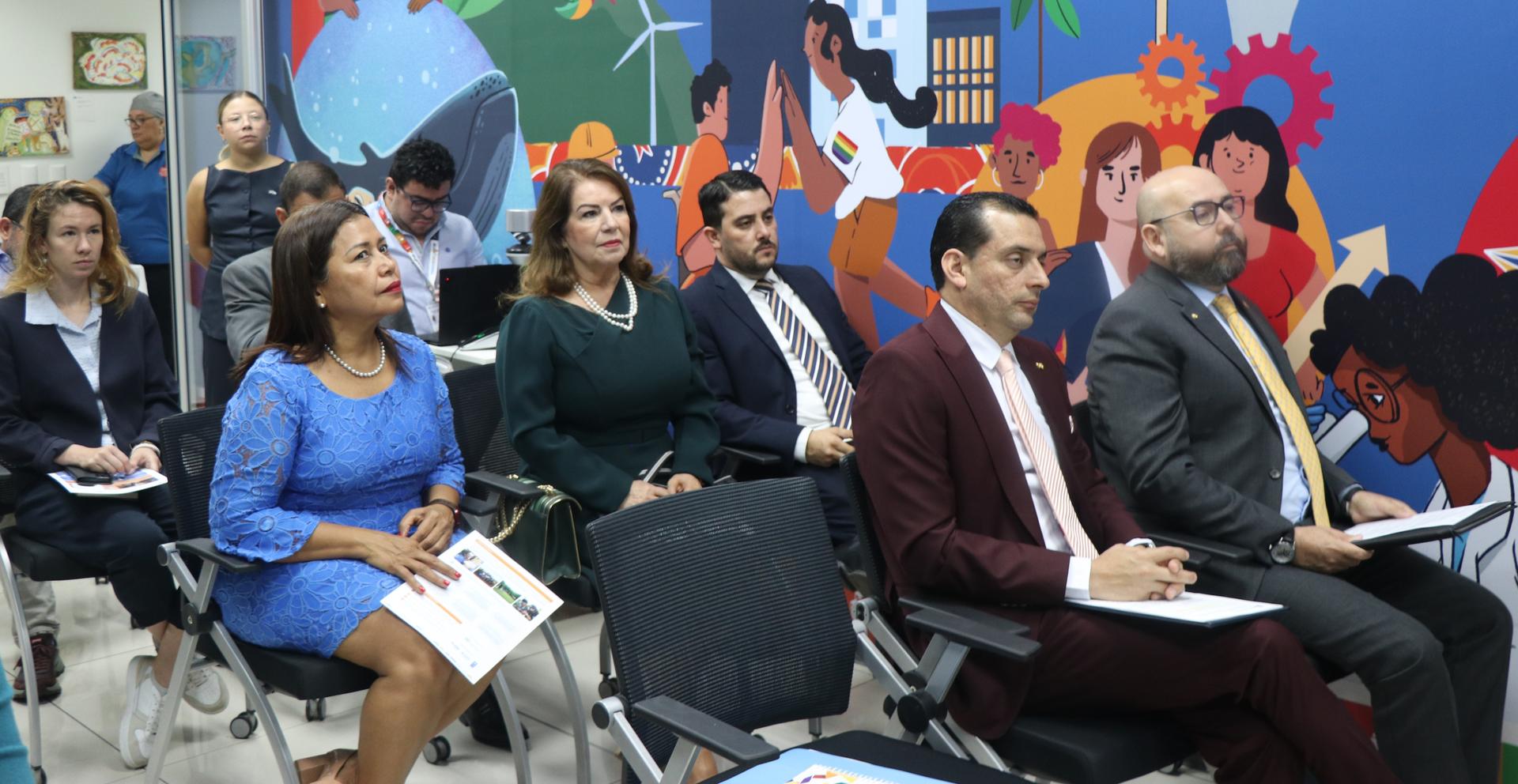 A diverse group of people seated in a conference room, engaged and attentive.