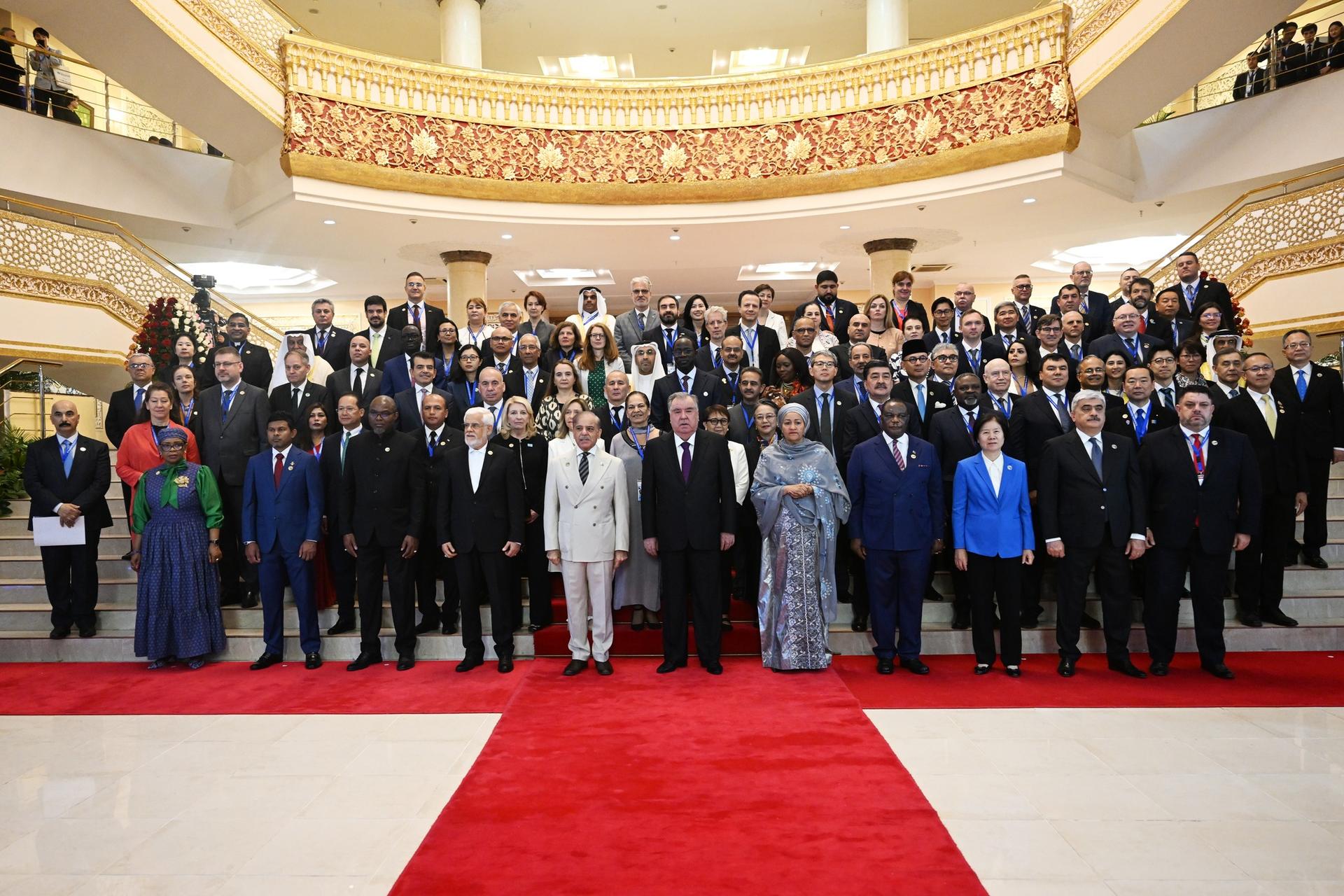 A large group of diverse individuals posing together on a red carpeted staircase.