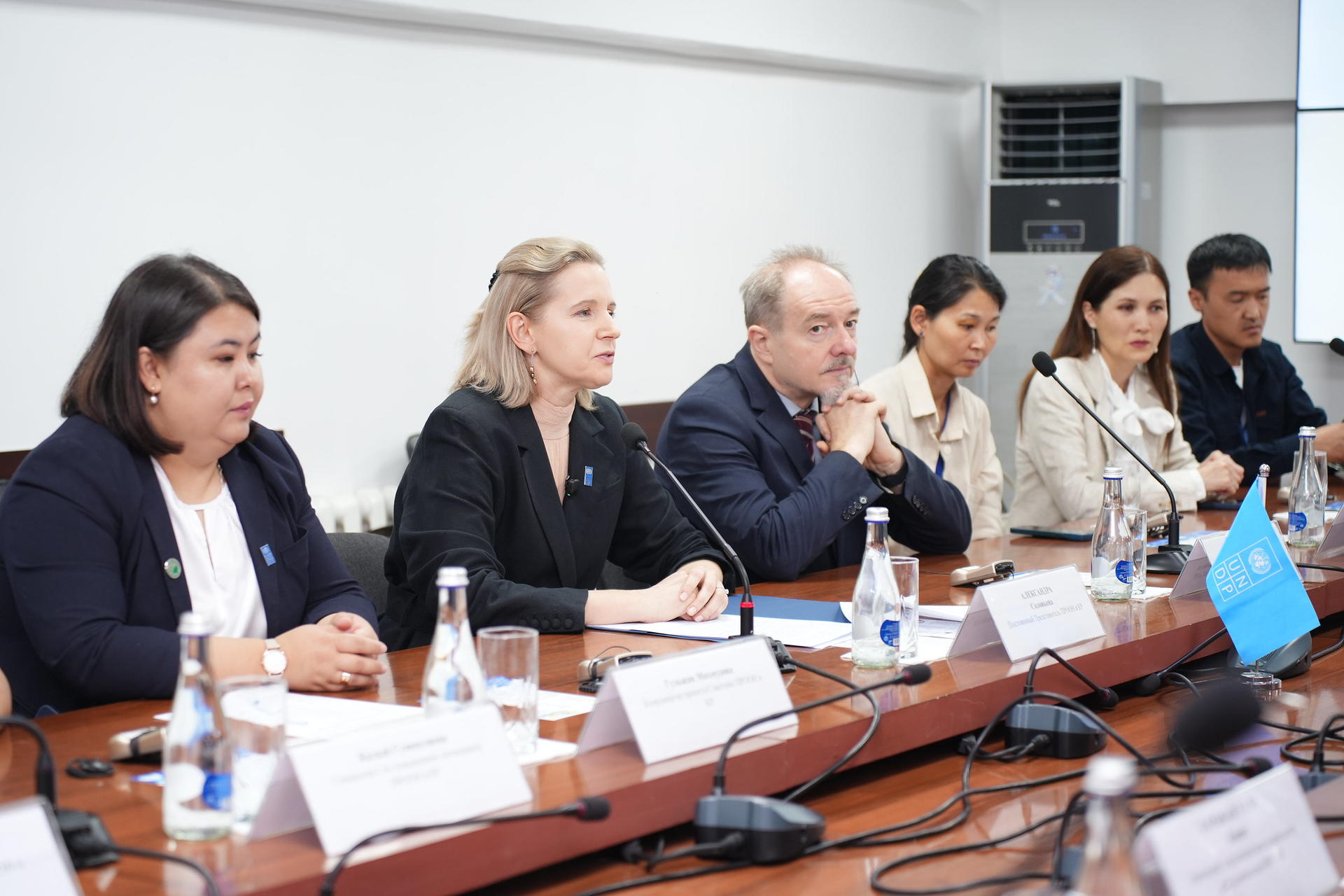 A diverse group of people seated at a table during a formal meeting or discussion.