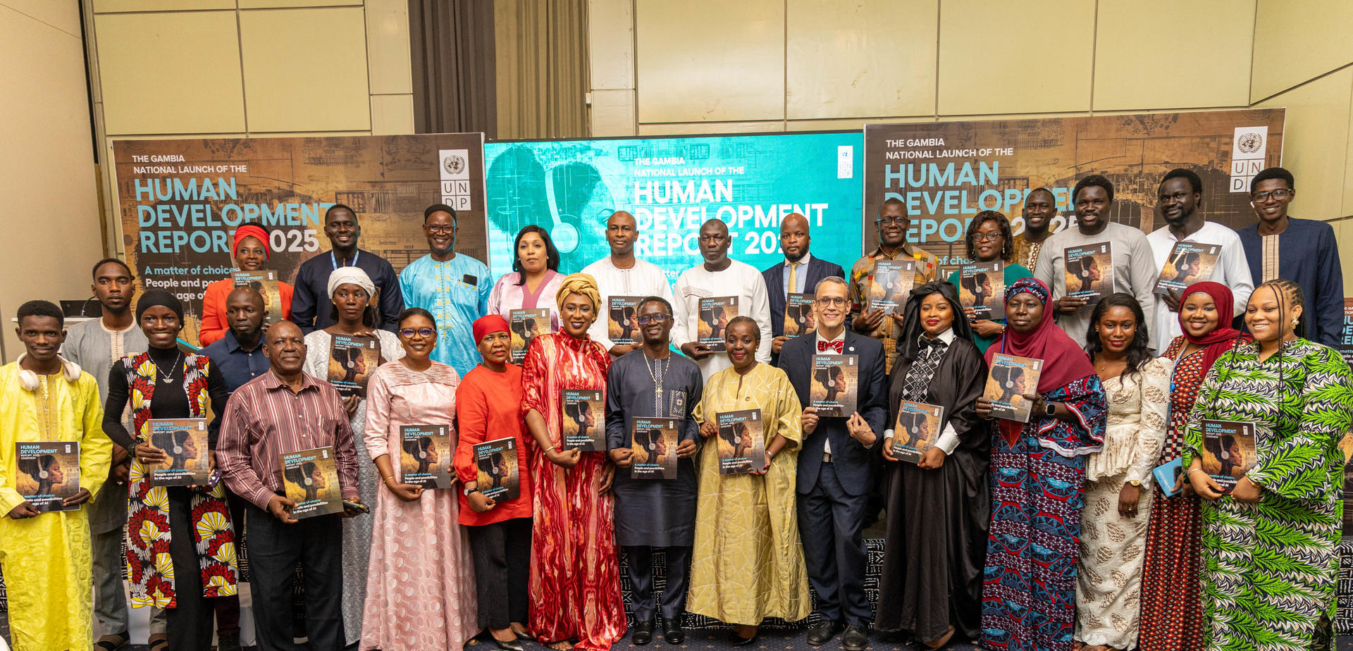 Group photo of diverse individuals holding books, standing in a conference room setting.
