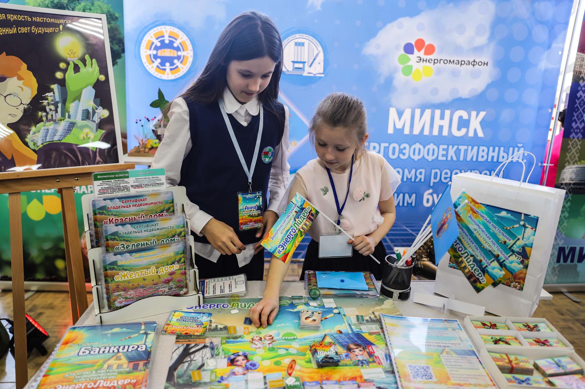 Two young girls engage with colorful materials at a table, surrounded by educational displays.