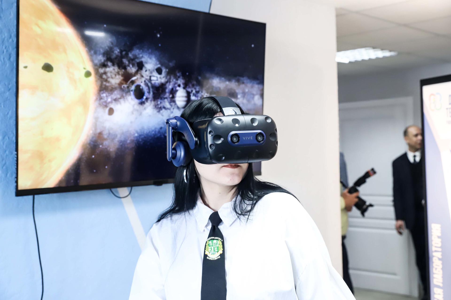 A person wearing a VR headset stands in front of a space-themed display.