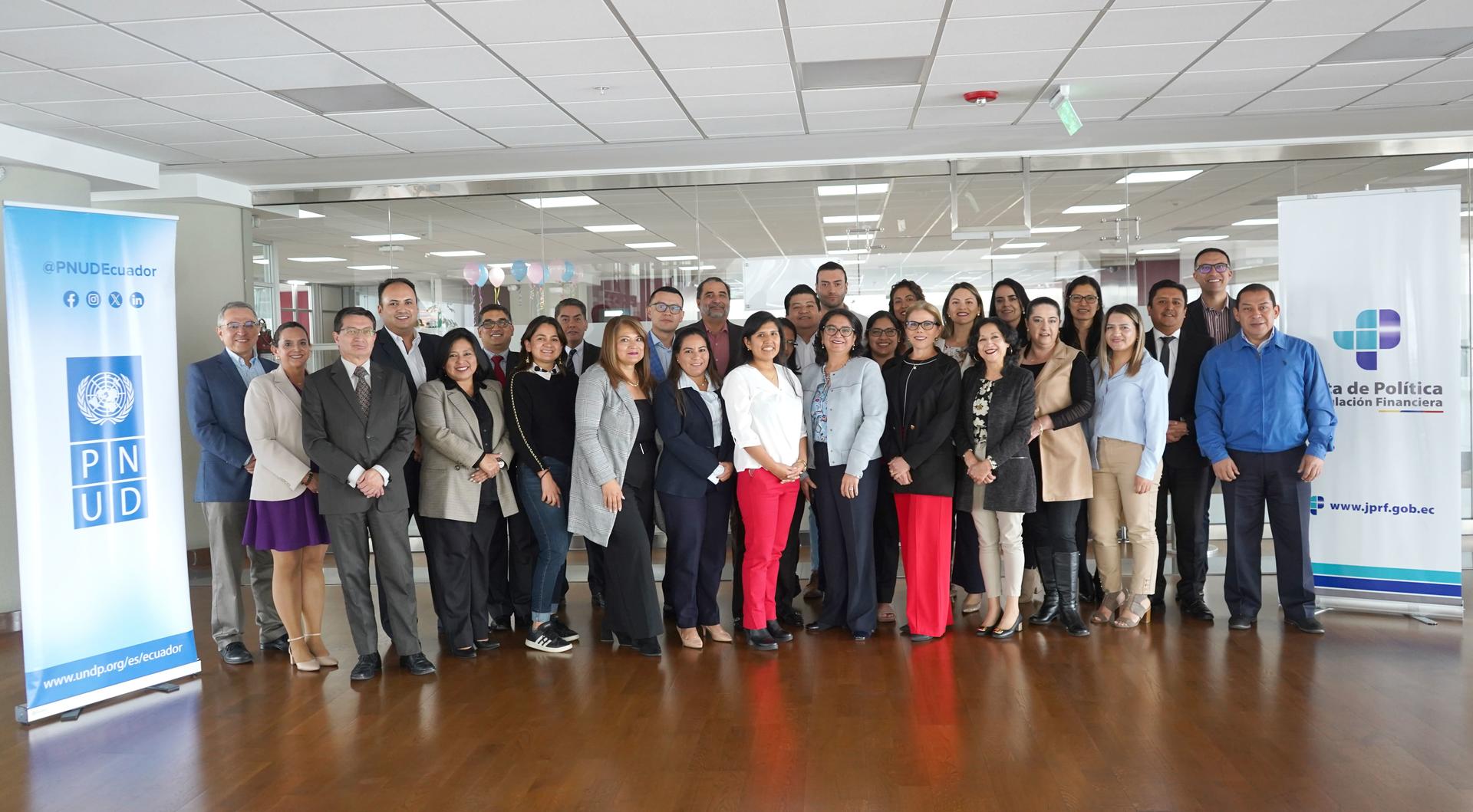 Group photo of diverse individuals standing together in a well-lit indoor space.