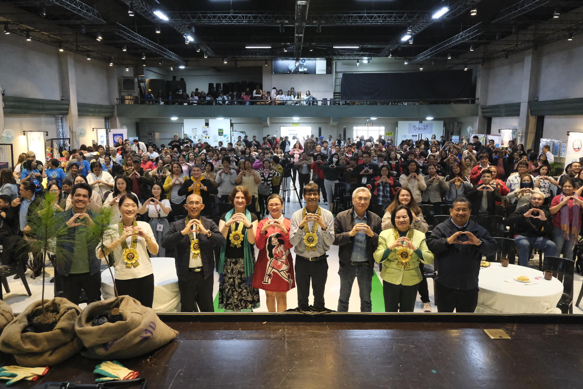 A large crowd gathered in a hall, with a group of people posing in the foreground.