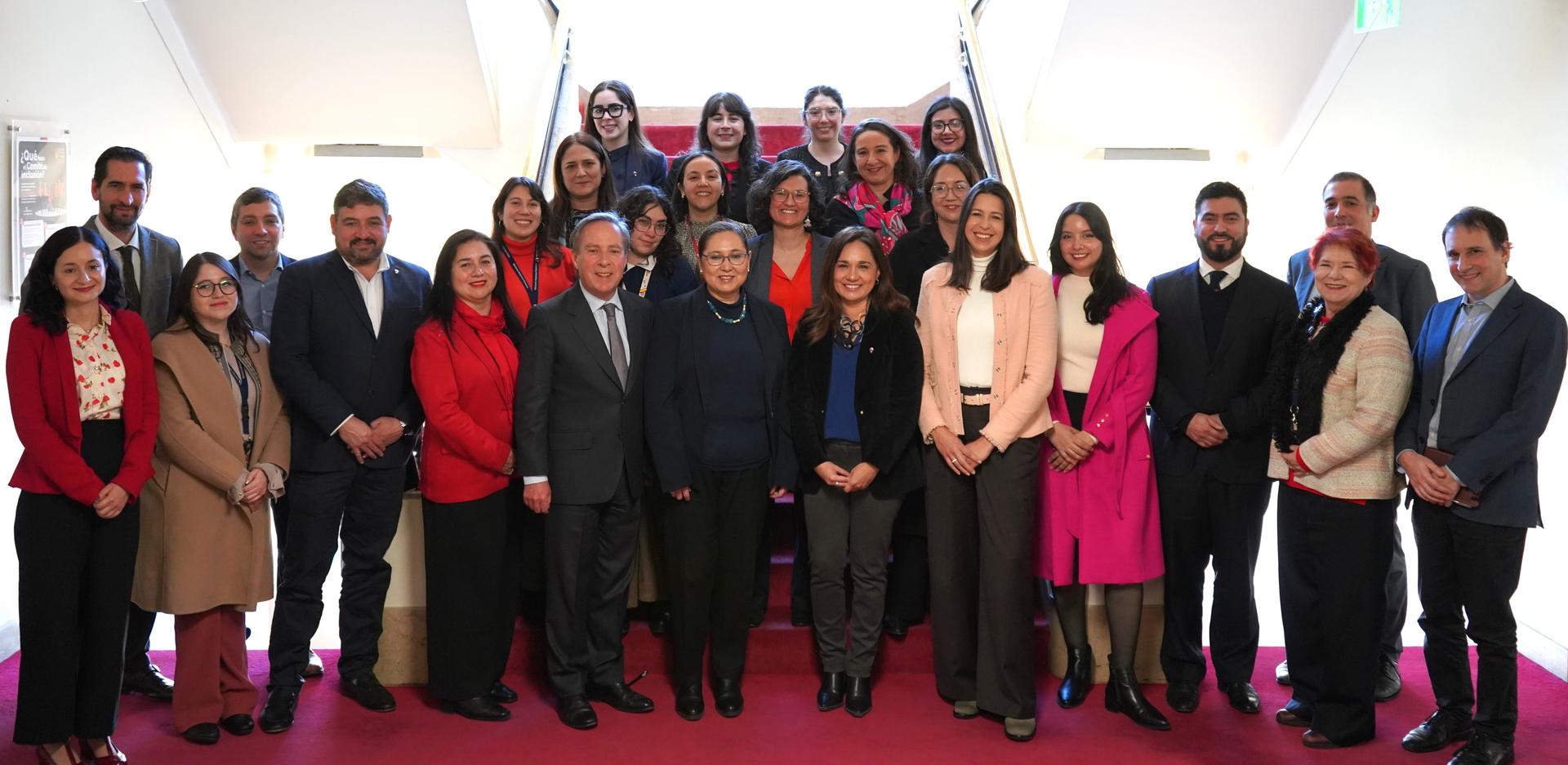 Group photo of diverse individuals standing on a staircase, smiling and dressed in professional attire.