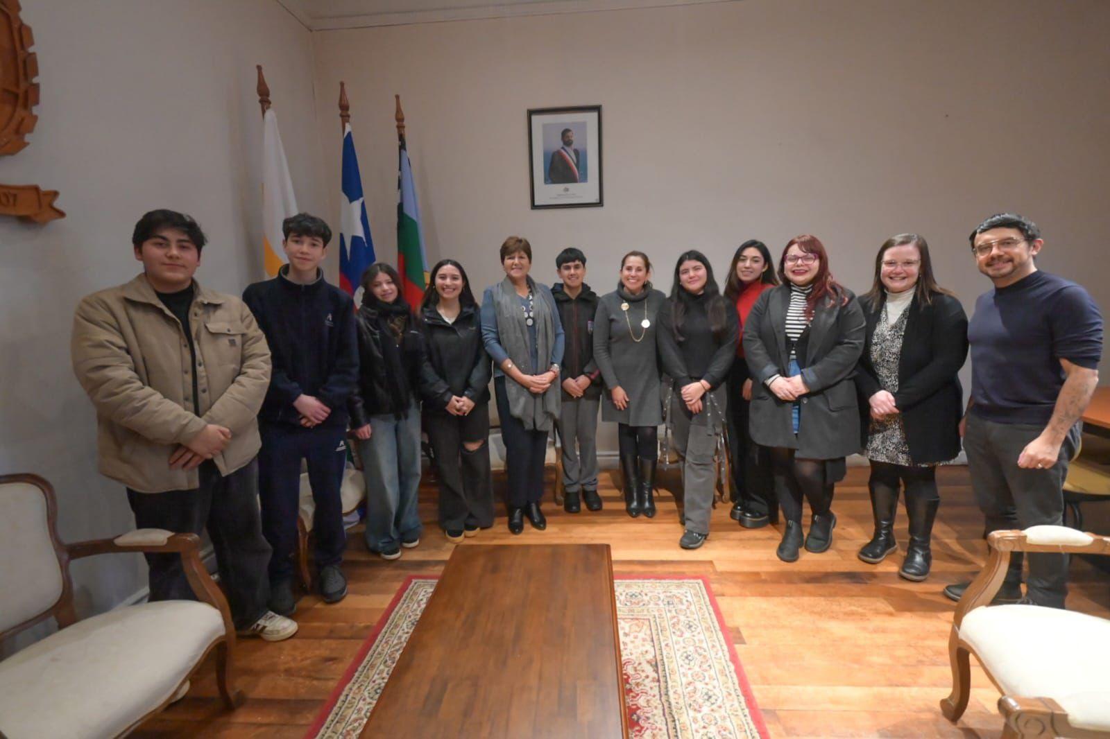 A group of diverse individuals poses together in an indoor setting with flags in the background.