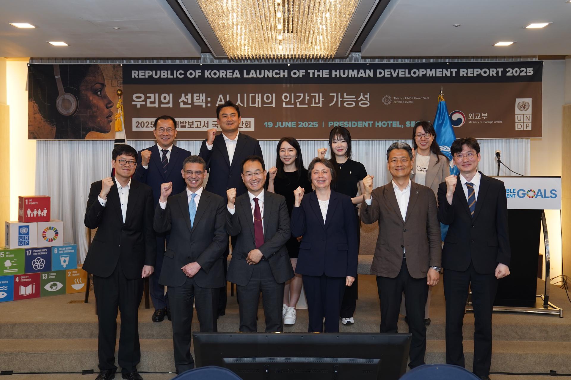 Group of ten professionals standing together, smiling and raising fists in celebration at an event.