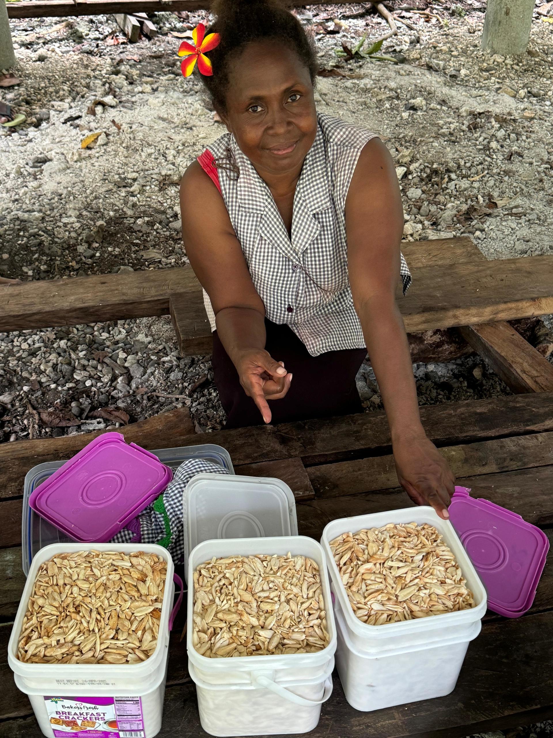 Woman sitting at a table with three containers of food, smiling and pointing.