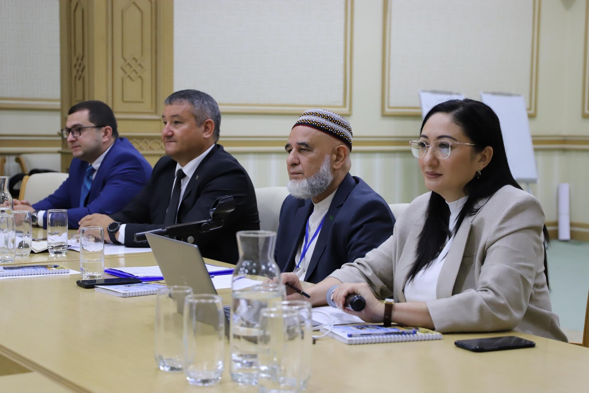 A diverse group of professionals seated at a conference table, engaged in discussion.