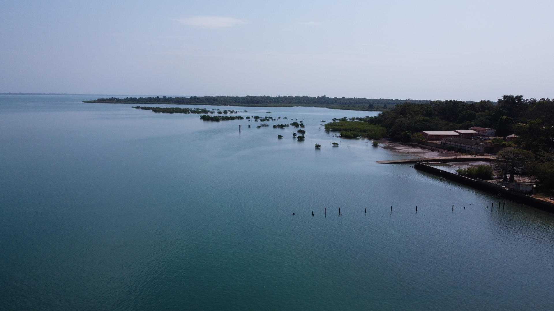Aerial view of a calm lake surrounded by greenery and distant land.