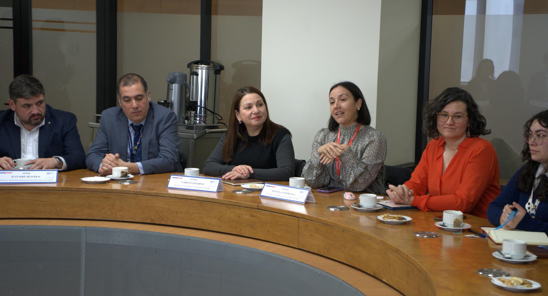 Group discussion around a round table with coffee cups, featuring engaged participants.