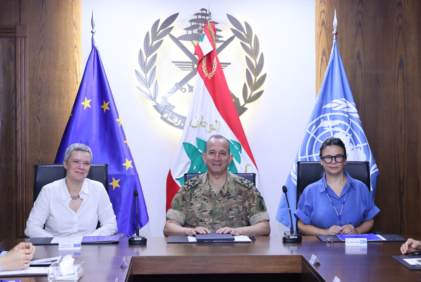 Three officials seated at a table, flags of the EU, Lebanon, and UN displayed behind them.