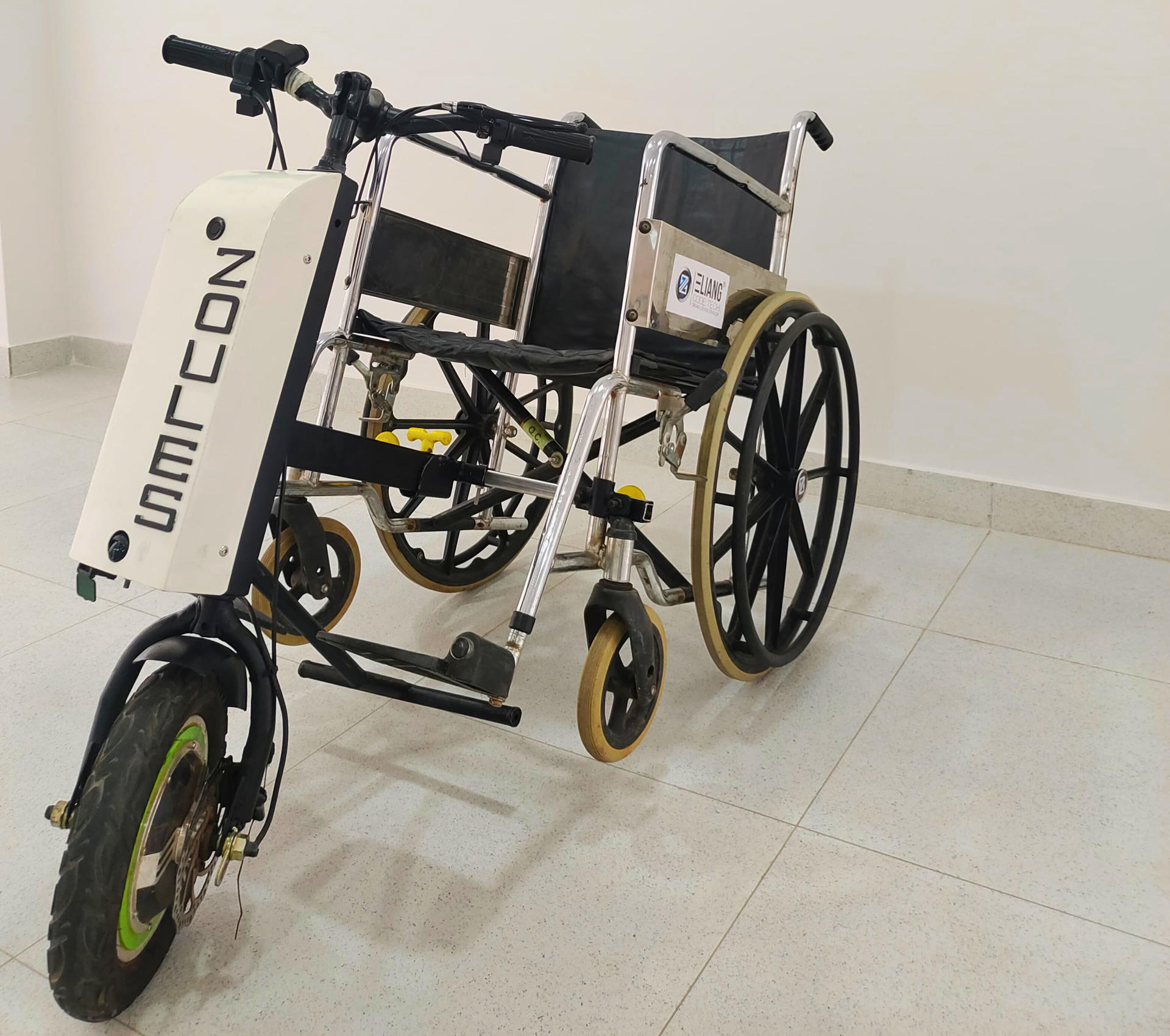 A hybrid wheelchair with two large wheels and a bicycle-like front, set on a tiled floor.