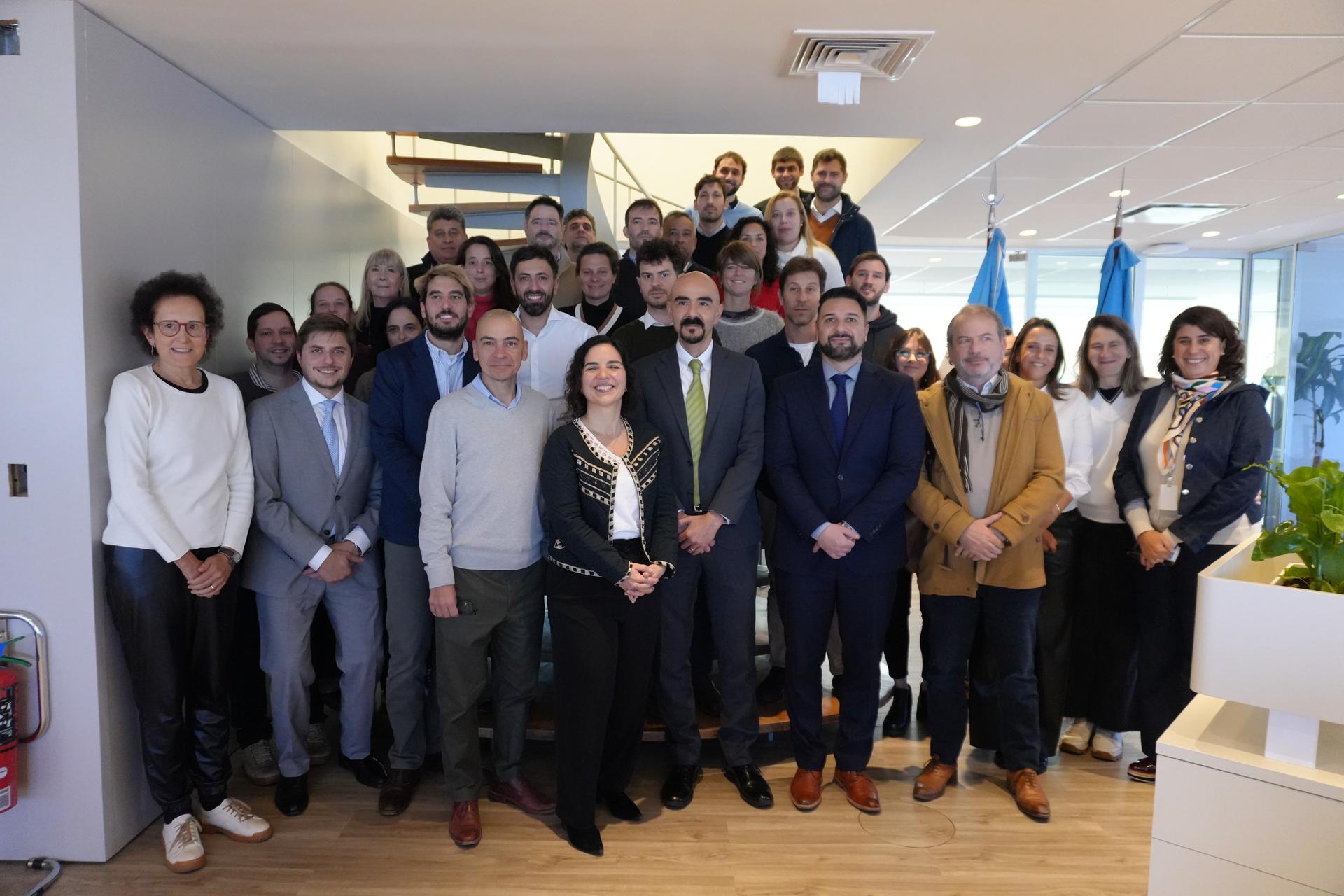 Un grupo de profesionales posando juntos en una oficina con una escalera en el fondo.