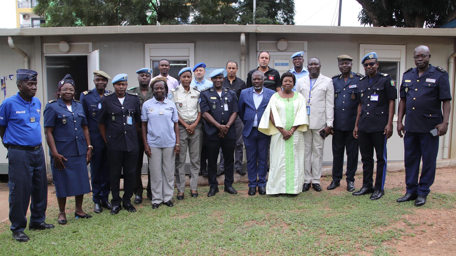 Group photo of diverse individuals in uniforms and formal attire, standing outdoors.
