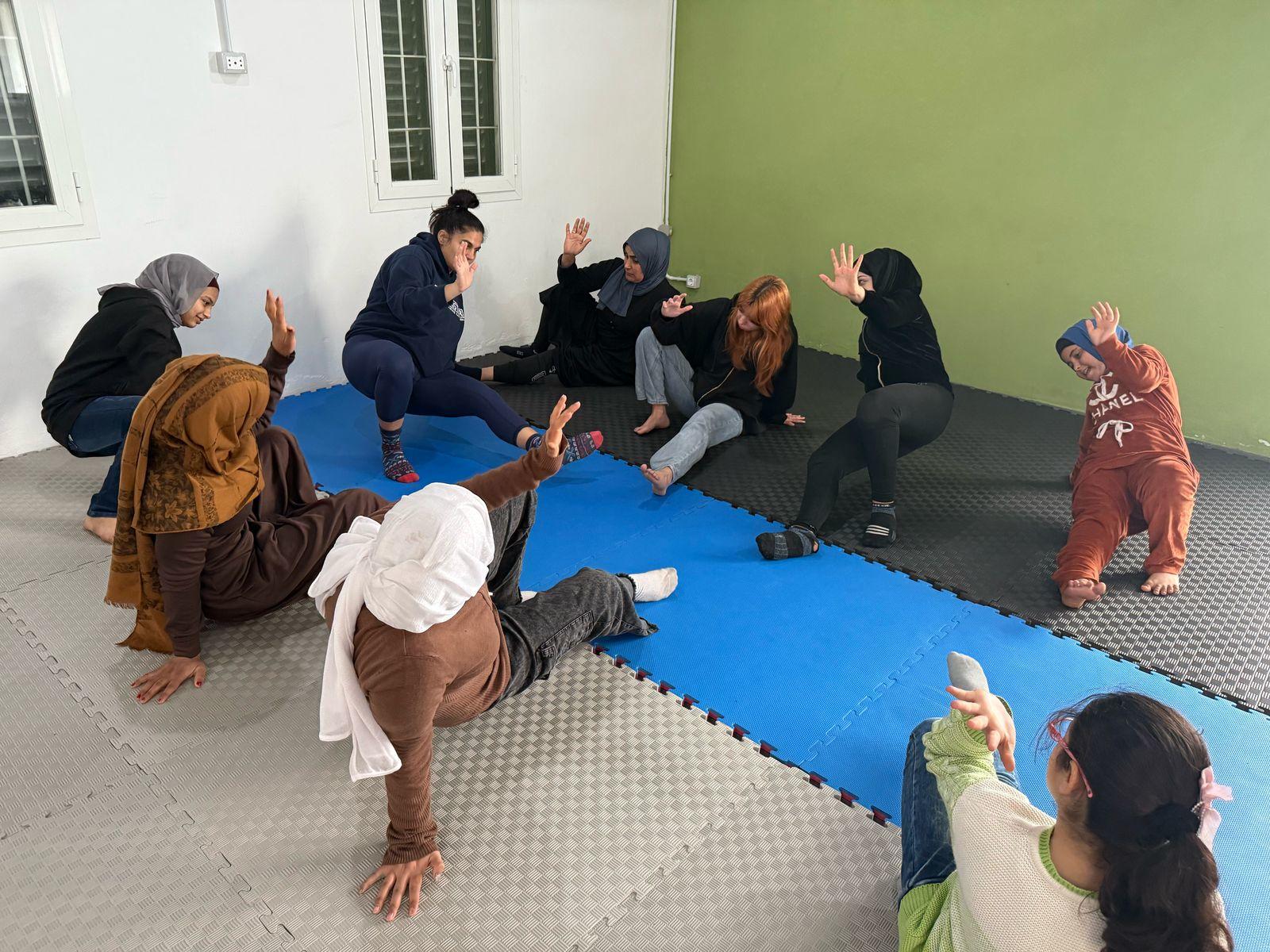 A group of people practicing a physical activity in a studio with blue mats.