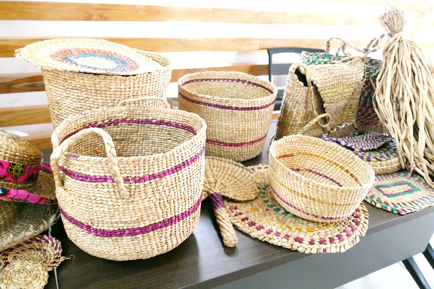 Woven straw baskets in various sizes, decorated with colorful patterns on a table.
