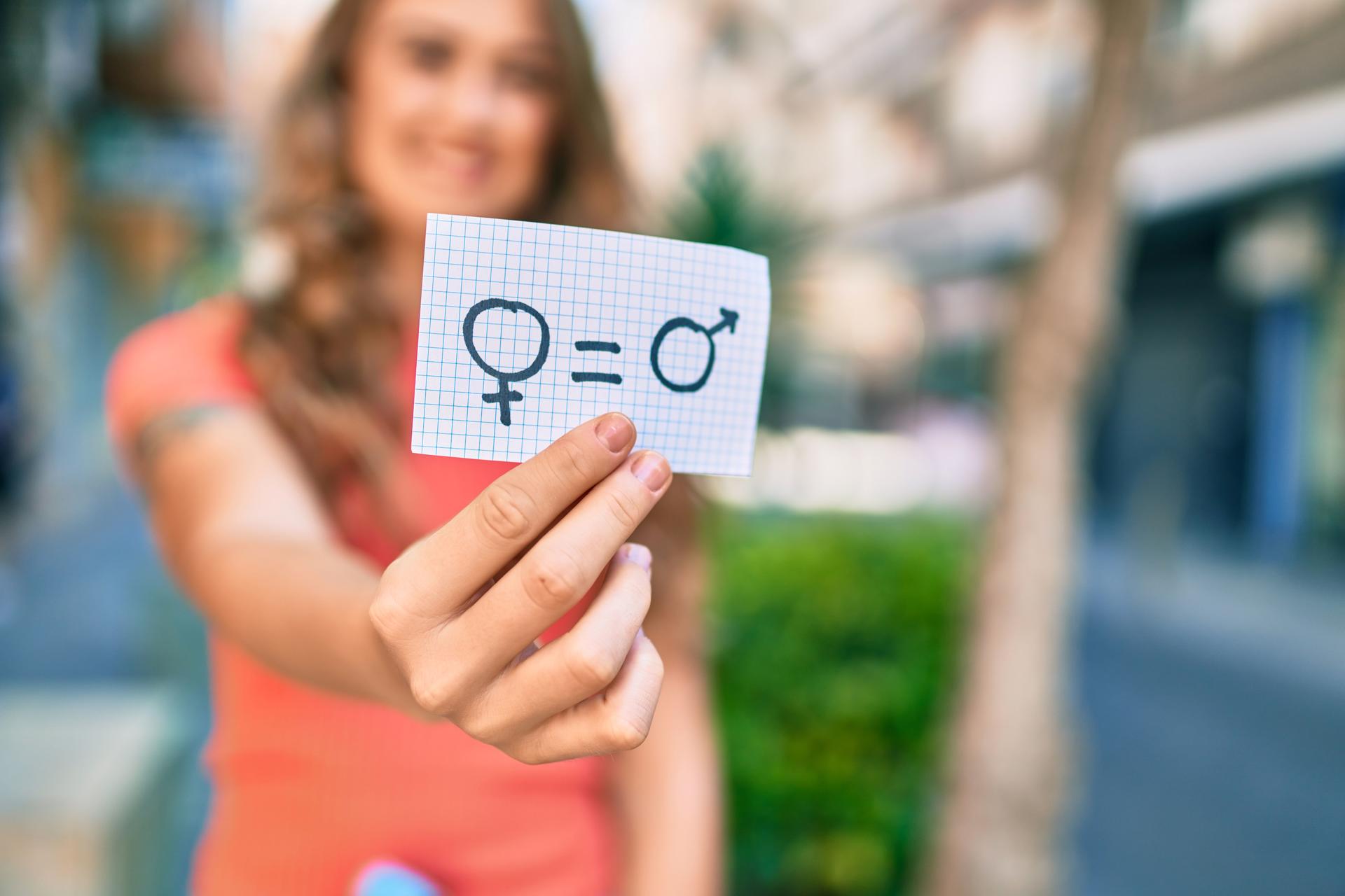 Una persona sosteniendo una tarjeta con símbolos de hombre y mujer