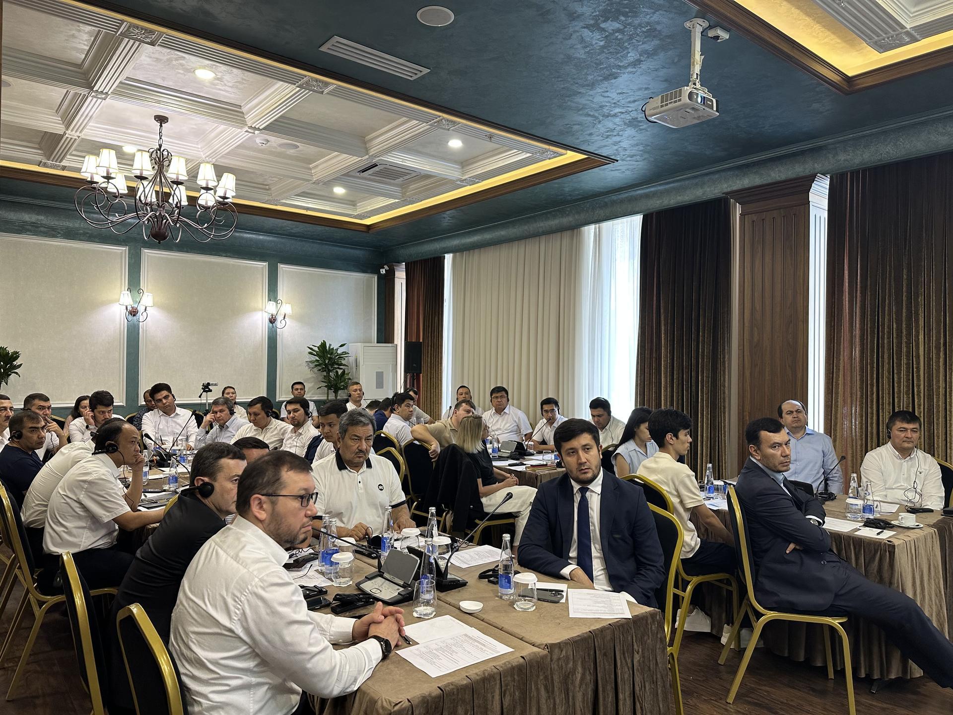 A group of professionals seated in a brightly lit conference room engaged in discussion.