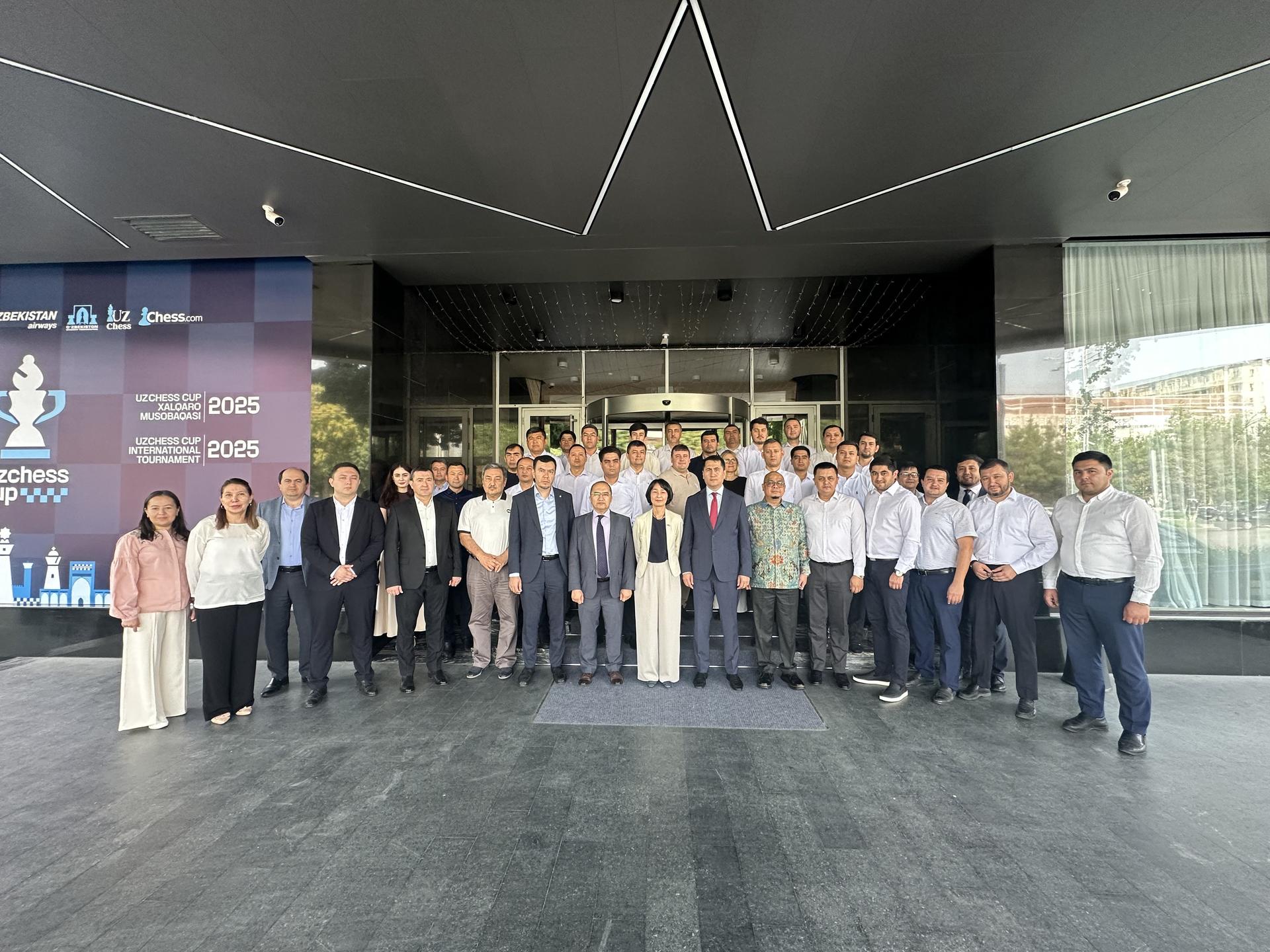 A large group of diverse individuals poses for a photo outside a modern building.