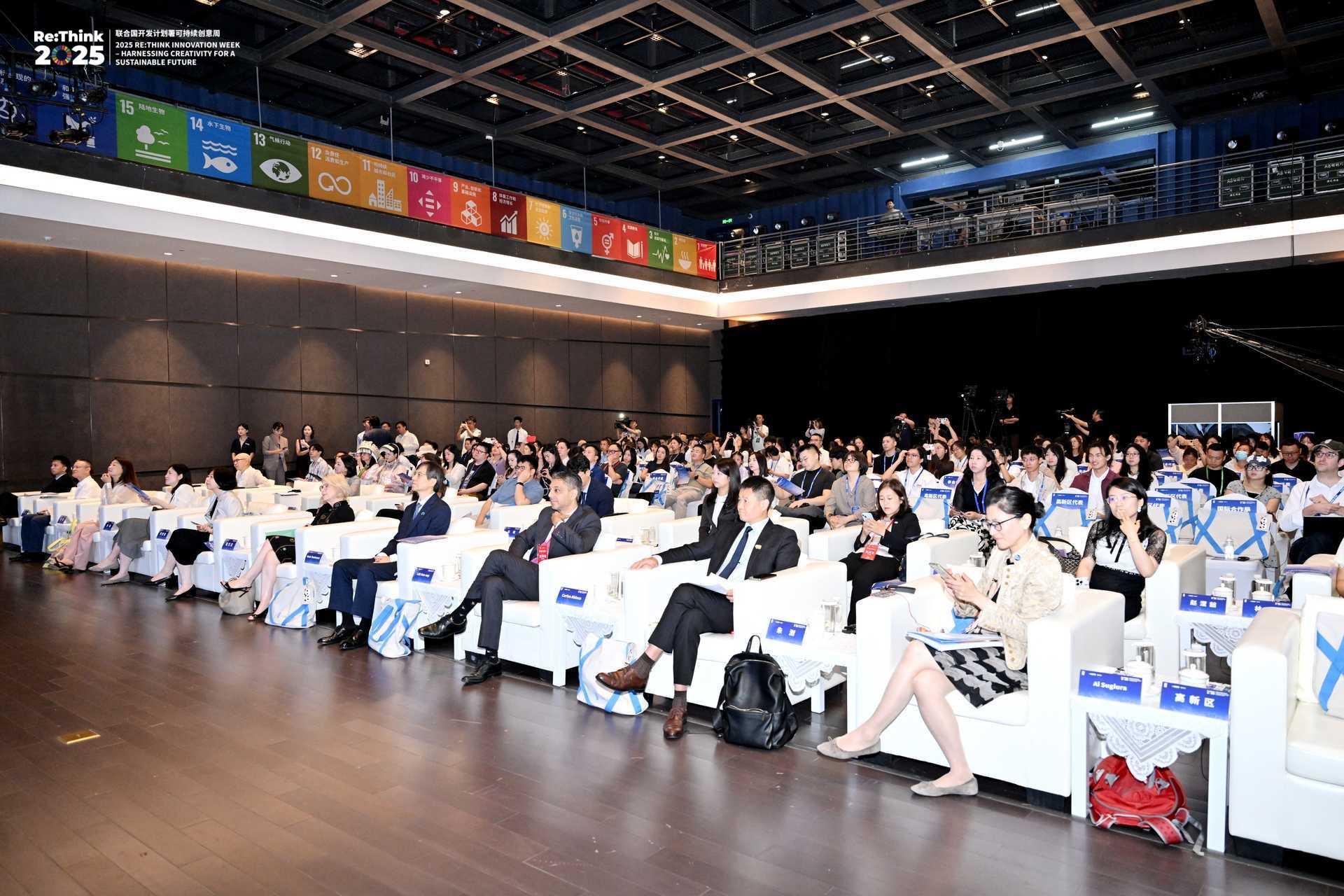 Conference attendees sitting in a modern auditorium, engaged in discussions.