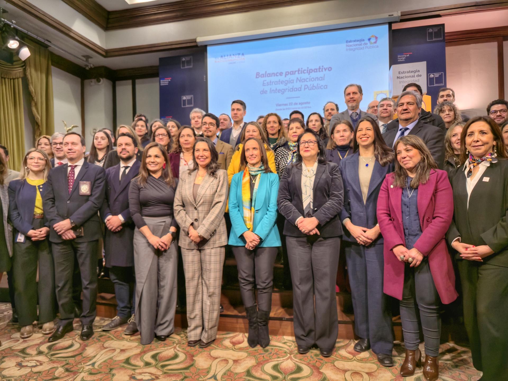 A large group of professionals standing together in a formal setting, smiling at the camera.
