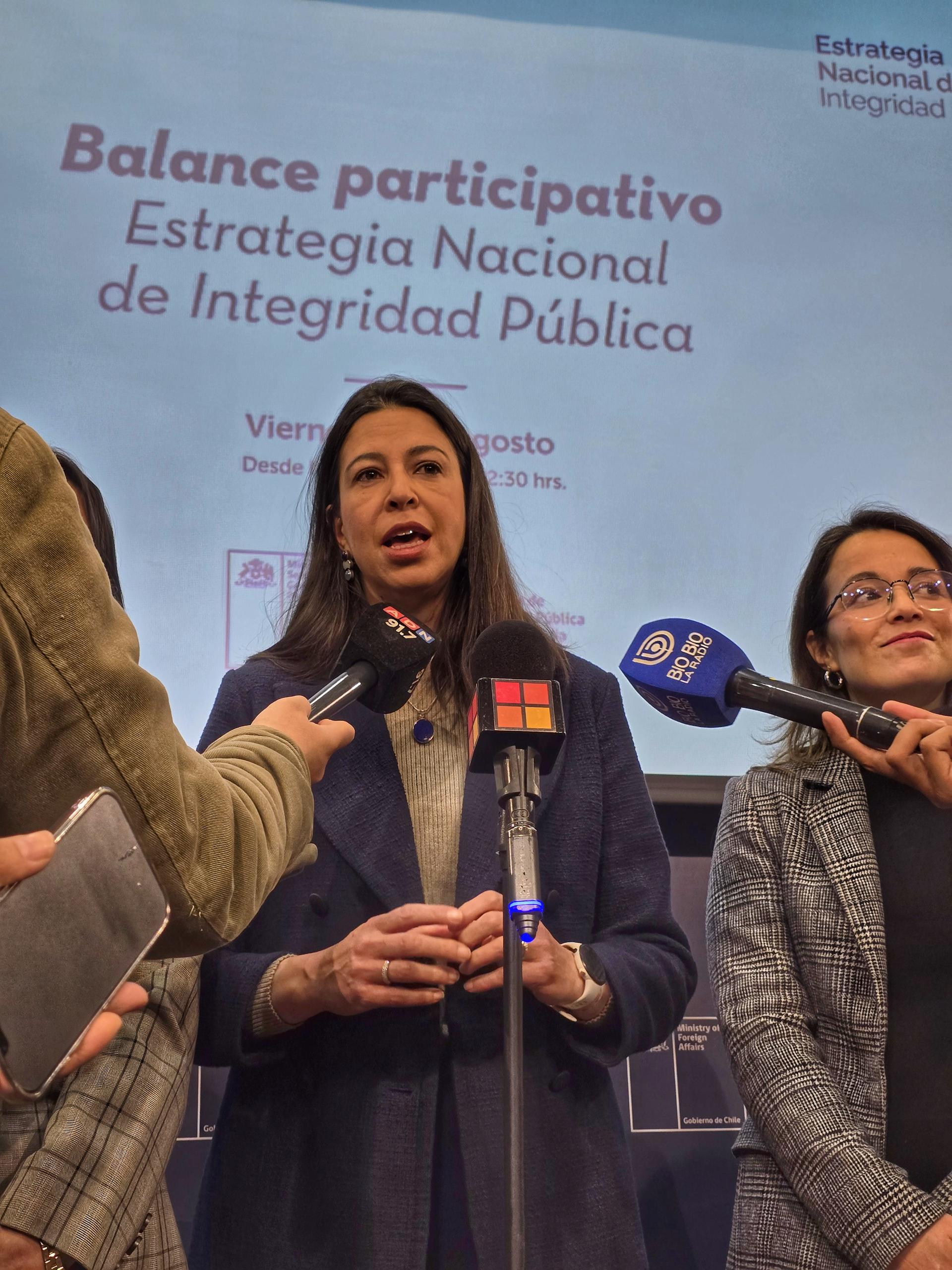 A woman speaking at a press conference, with another woman beside her, both holding microphones.