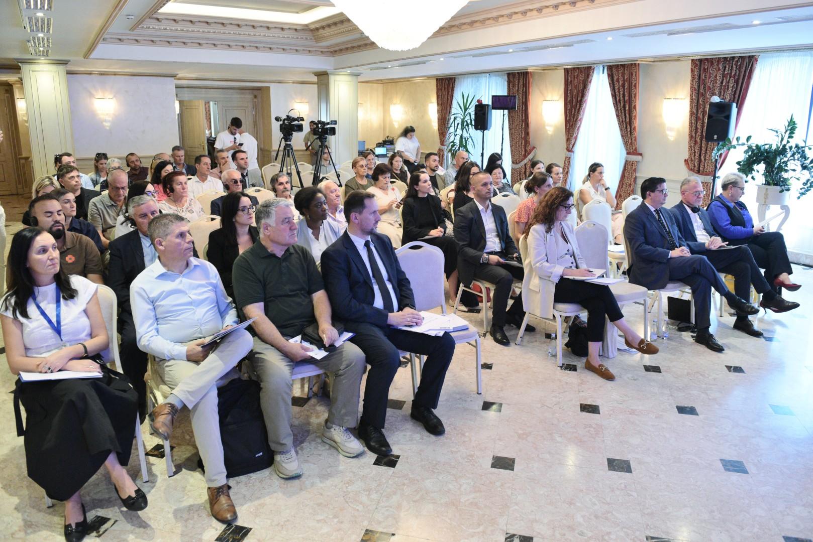 Audience seated in a conference room, engaged in a presentation.
