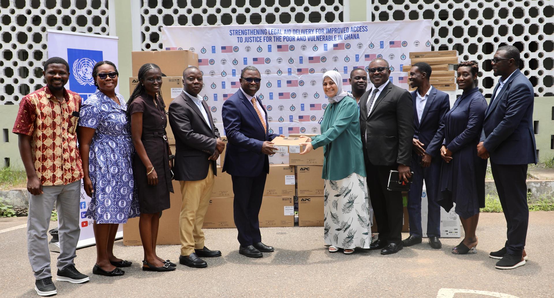 Group of professionals exchanging documents in front of a wall with logos and boxes.