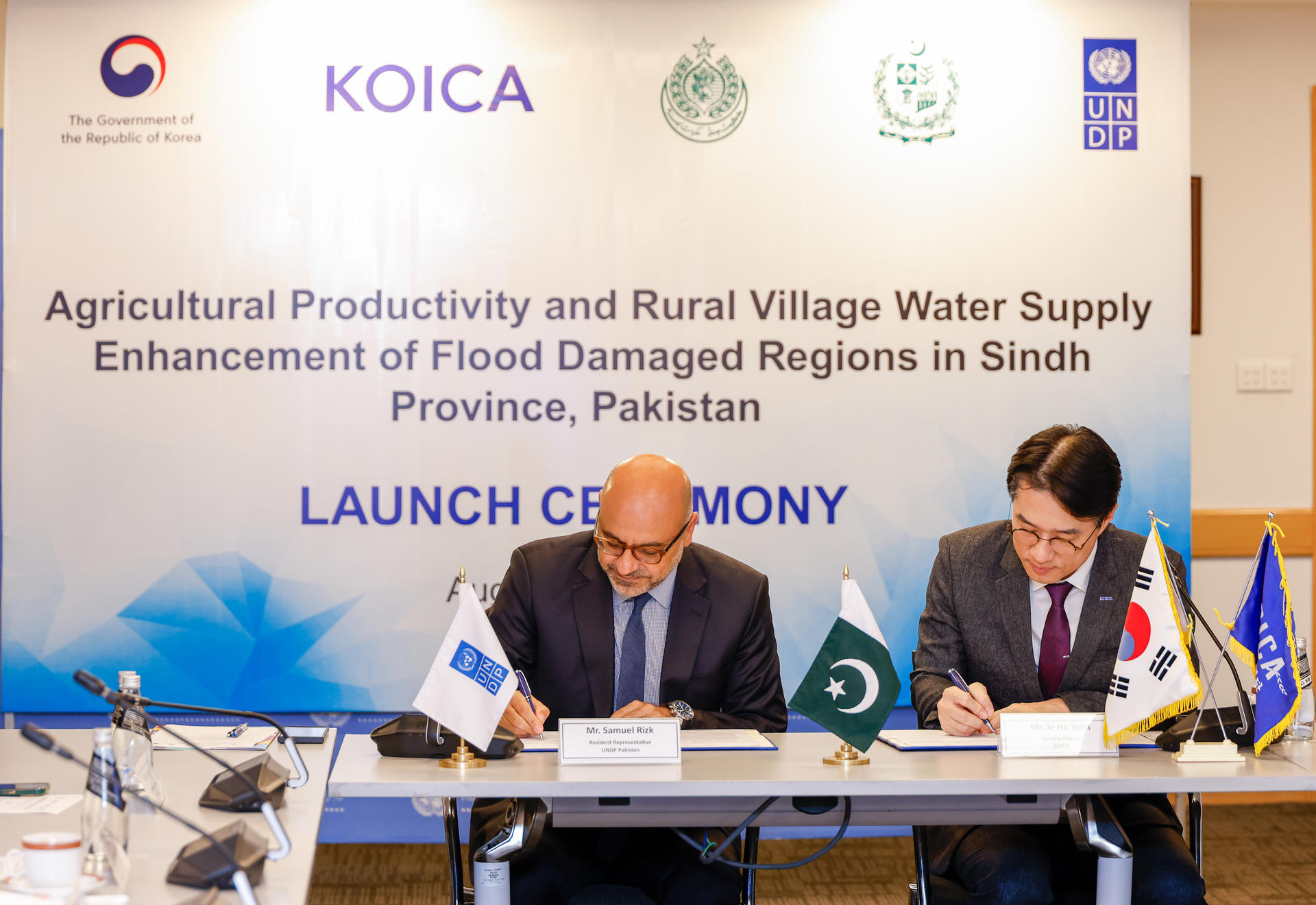 Two men signing documents at a launch ceremony for a water supply project in Pakistan.