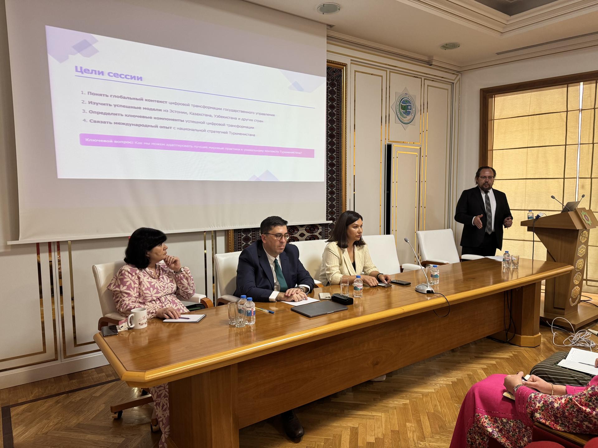 Panel discussion at a conference with four speakers and a presentation displayed.