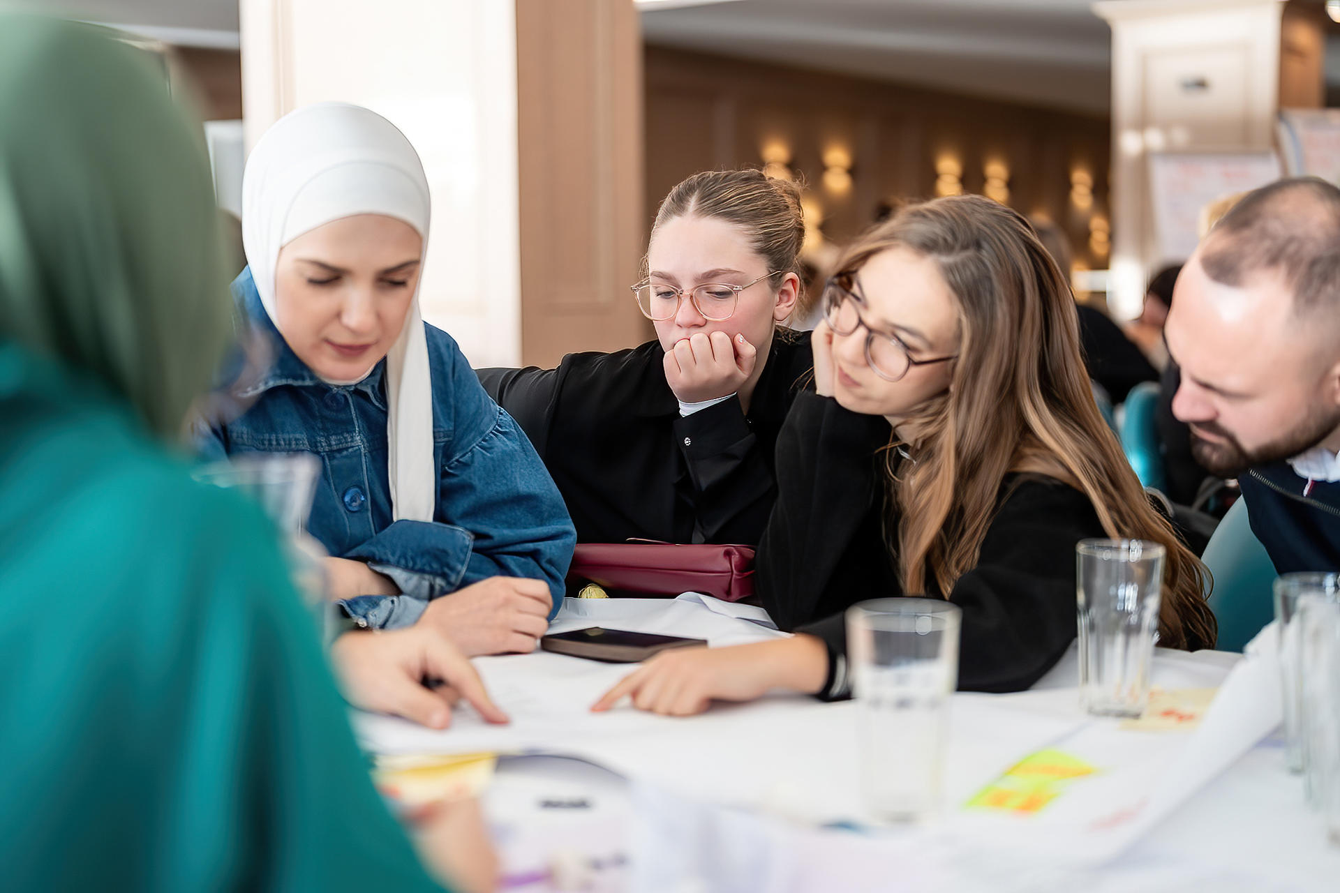A group of diverse individuals engaged in discussion around a table, focused and contemplative.