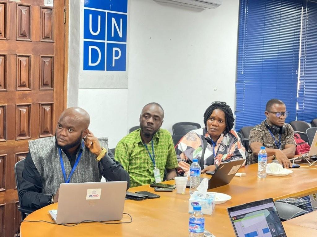 A group of professionals seated at a conference table with laptops and water bottles.