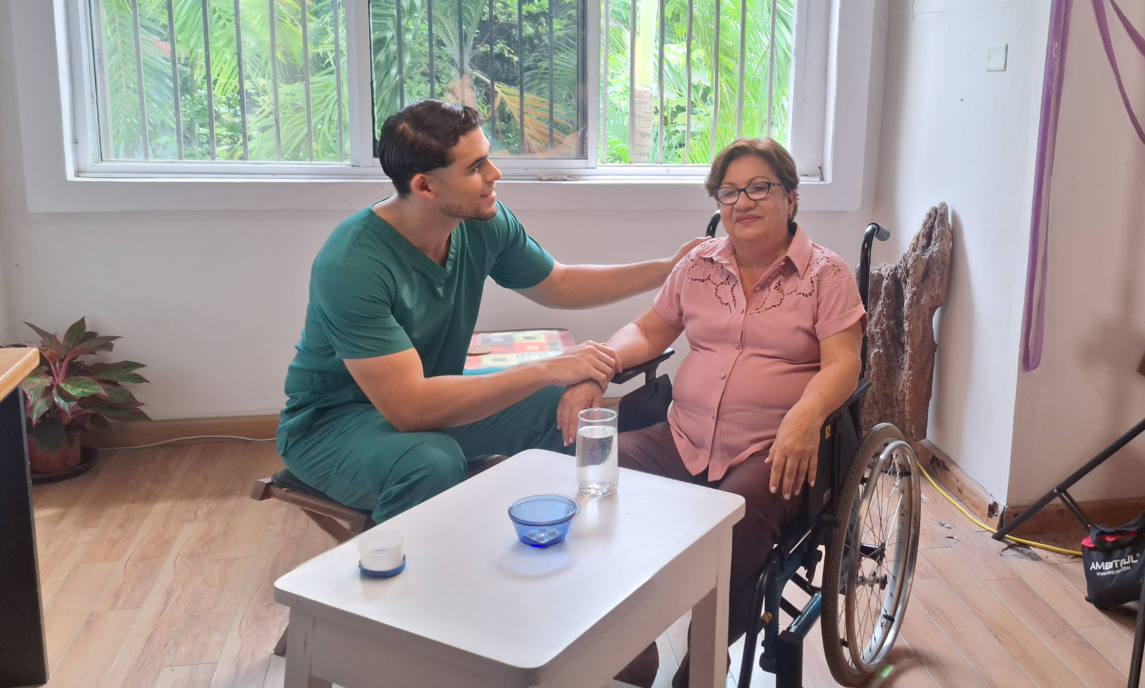 Un profesional de la salud conversa con una mujer en silla de ruedas
