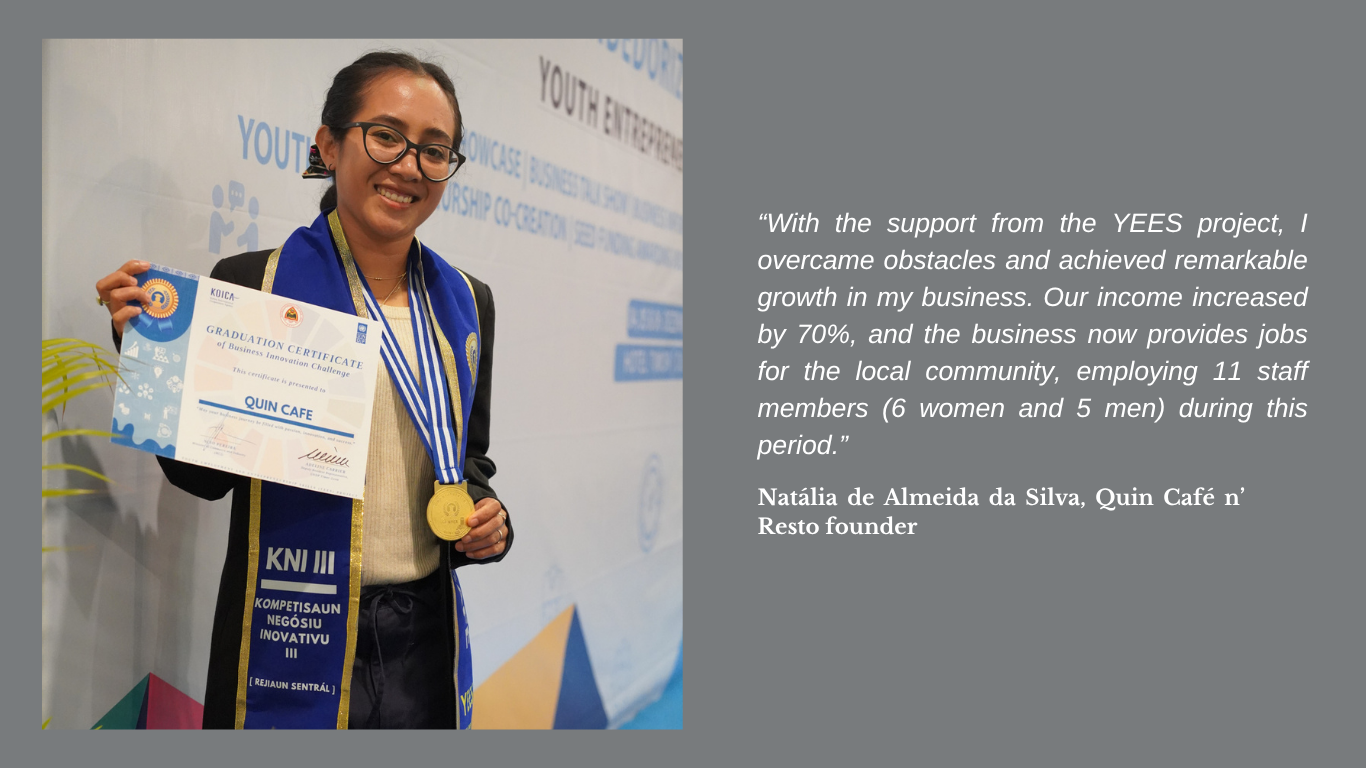A woman smiles while holding a certificate and gold medal at an event, wearing a graduation sash.