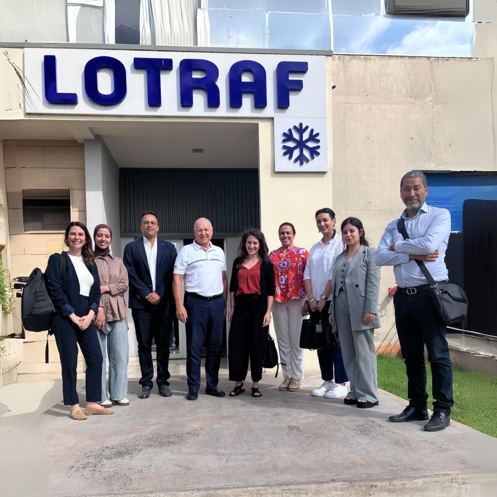 Group of people posing outside a building with a blue LOTRAF sign and snowflake logo.