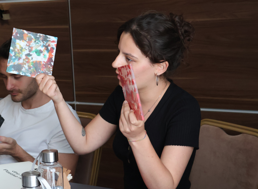 Photo of two diners at a restaurant booth; one holds a red card, the other a colorful card.